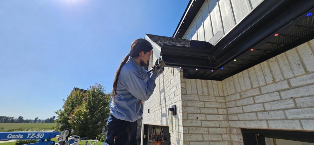 Installer mounting permanent outdoor lighting track along a soffit