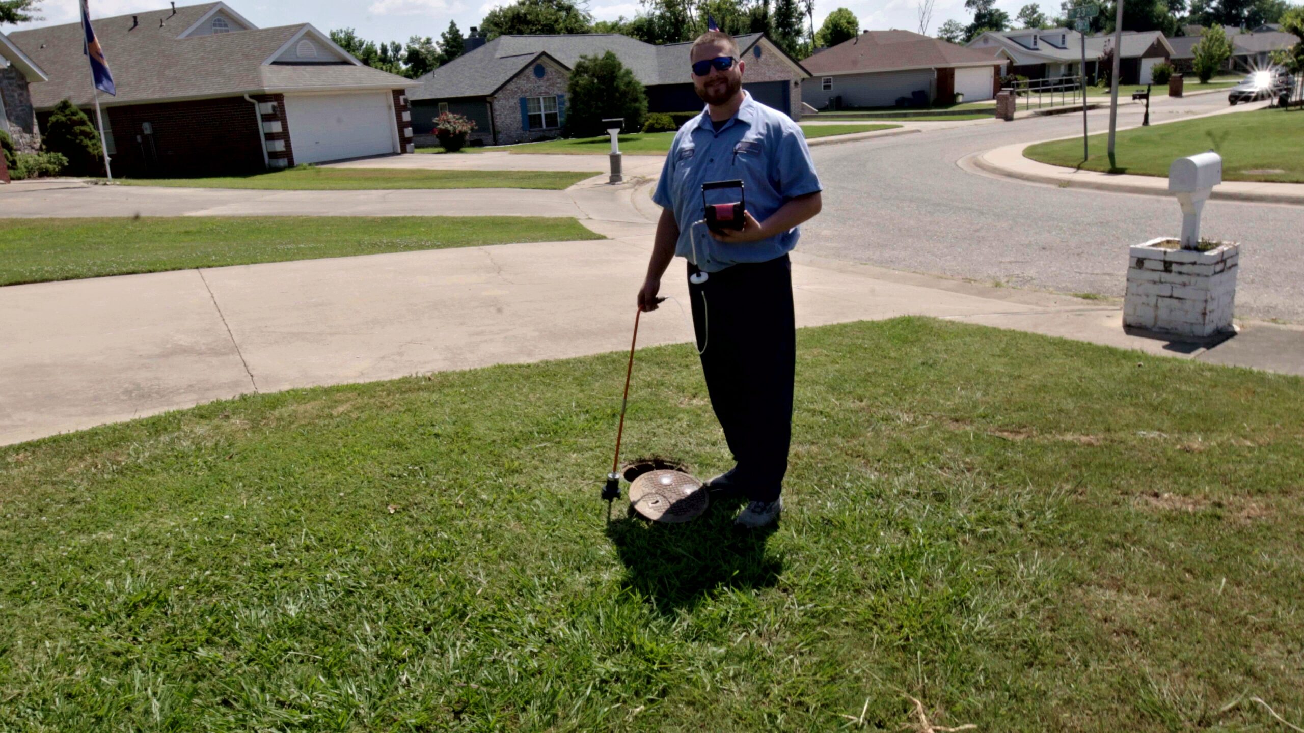 Smiling Paschal plumber next to a water meter after completing a leak detection service in Bentonville