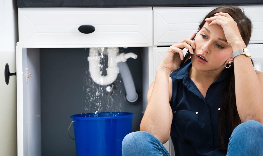 woman on phone leaking sink pipe e1631822728590